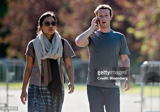 Mark Zuckerberg, chief executive officer and founder of Facebook Inc., right, talks on the phone while arriving for a morning session his wife...