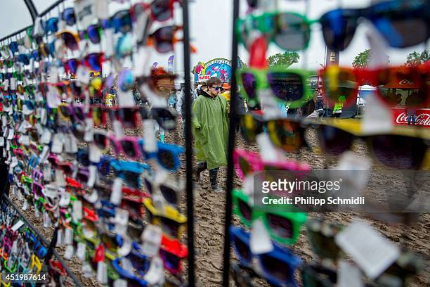 Festival-goer walks through mud and passes a sunglasses shop at Openair Frauenfeld on July 10, 2014 in Frauenfeld, Switzerland.