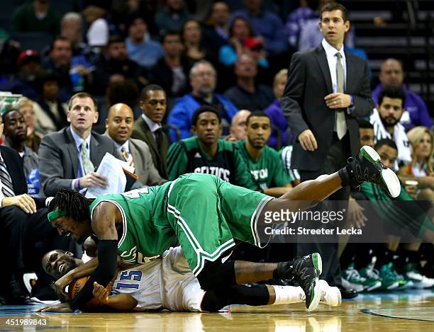 Kemba Walker of the Charlotte Bobcats and Gerald Wallace of the Boston Celtics fight for a loose ball during their game at Time Warner Cable Arena on...