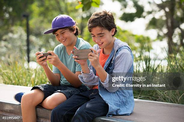 boys hanging out playing games on their phones. - jugendkultur sitzen konsole stock-fotos und bilder