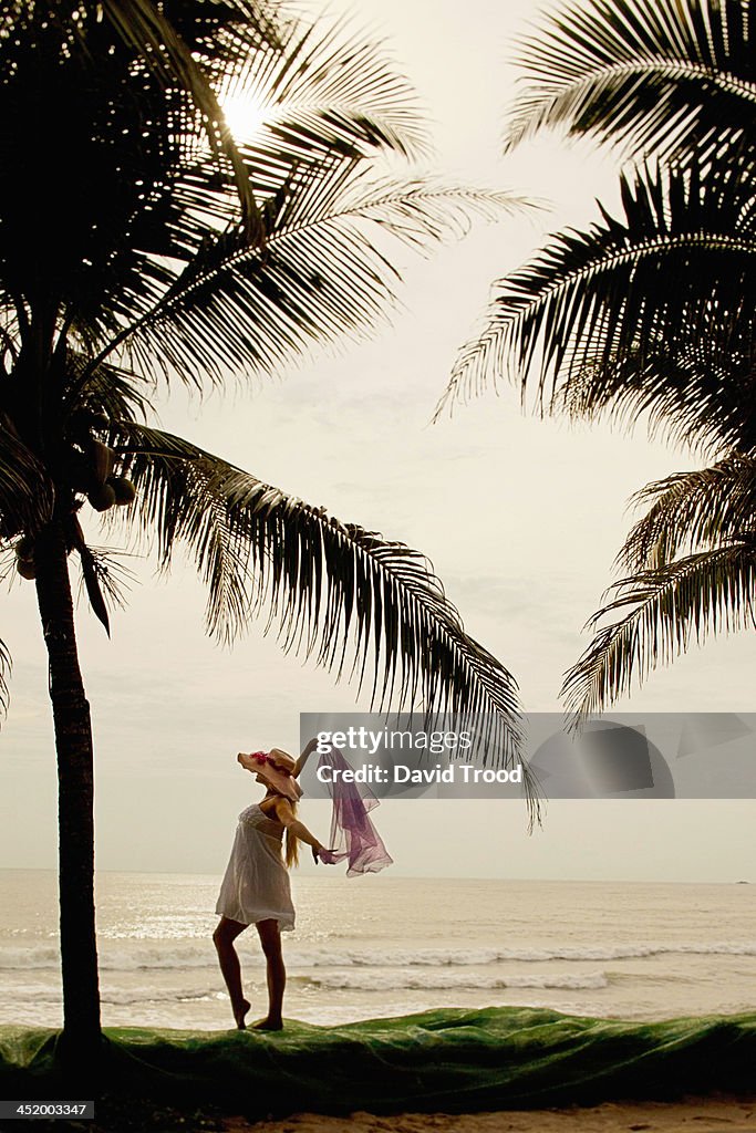 Young woman holding scarf on the beach