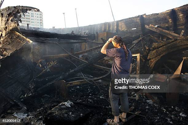 Canadian John Godfrey, a chief member of the peace activist boat "Gaza's Ark", checks the damage to his burnt boat following an Israeli air strike...
