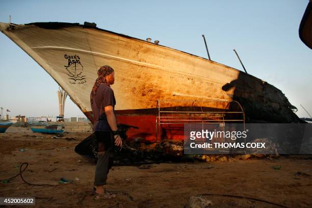 Canadian John Godfrey, a chief member of the peace activist boat "Gaza's Ark", checks the damage to his burnt boat following an Israeli air strike...