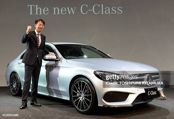 Mercedes Benz Japan president Kintaro Ueno poses beside the company's new C-class sedan during its press preview in Tokyo on July 11, 2014. Mercedes...