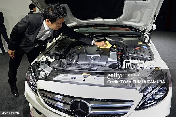 Mercedes Benz Japan employee cleans the engine of the company's new C-class sedan during its press preview in Tokyo on July 11, 2014. Mercedes Benz...