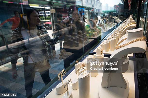 People look at gold jewelry displayed in the window of a Chow Tai Fook Jewellery Group Ltd. Store in the shopping district of Tsim Sha Tsui in Hong...