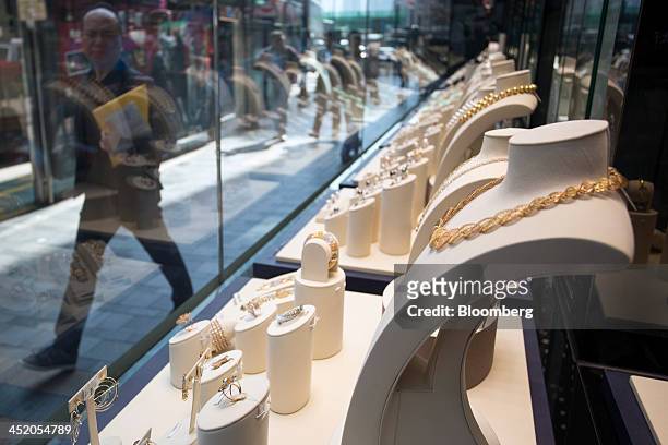Man walks past gold jewelry displayed in the window of a Chow Tai Fook Jewellery Group Ltd. Store in the shopping district of Tsim Sha Tsui in Hong...