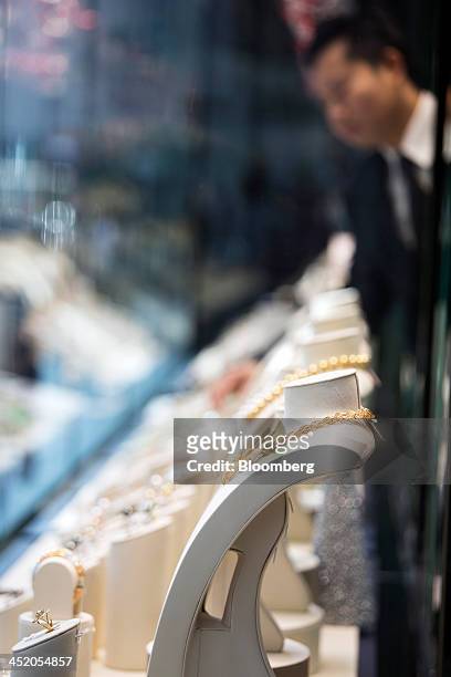 An employee arranges gold jewelry in the window display of a Chow Tai Fook Jewellery Group Ltd. Store in the shopping district of Tsim Sha Tsui in...