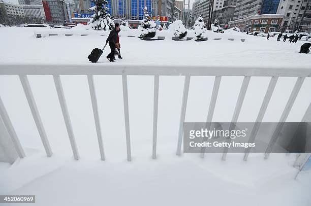People walk after a blizzard at Xipingxing Road at November 25, 2013 in Shuangyashan, Heilongjiang province of China. Highways and airports were all...