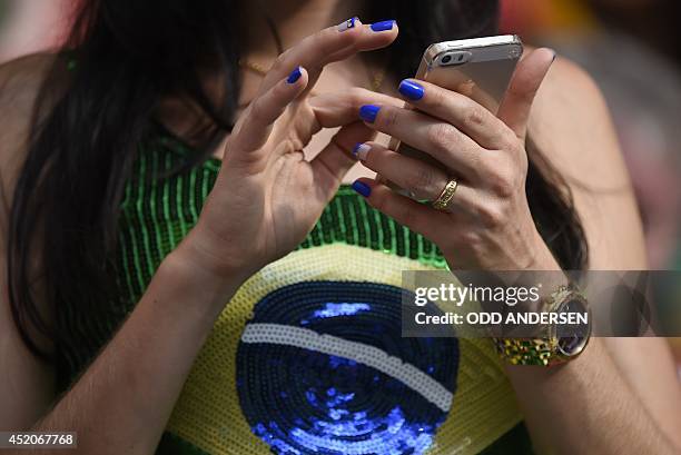Brazil fan uses a mobile phone prior to the third place play-off football match between Brazil and Netherlands during the 2014 FIFA World Cup at the...