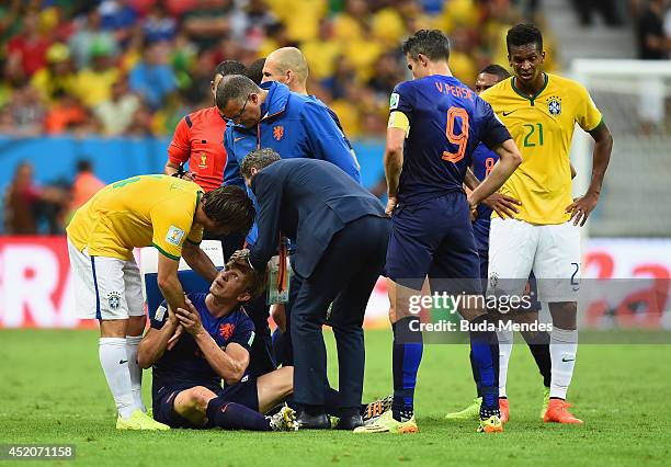 Dirk Kuyt of the Netherlands receives treatment after a clash as Maxwell of Brazil stands over during the 2014 FIFA World Cup Brazil Third Place...