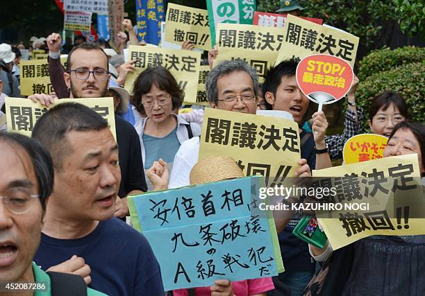 Protesters hold placards demanding the "withdraw of the cabinet decision" and shout anti-Abe government slogans during a rally in front of the...