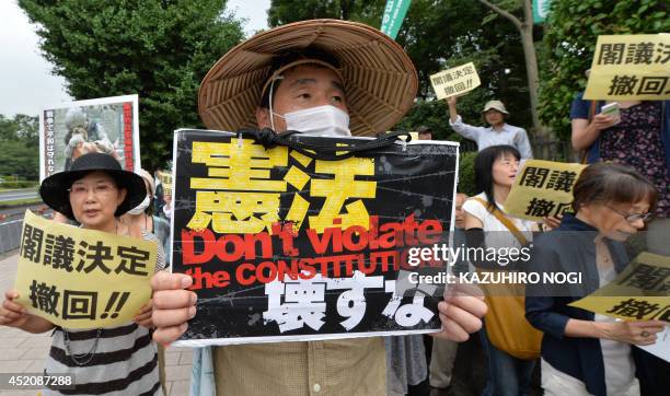 Protesters hold placards demanding the "withdraw of the cabinet decision" and shout anti-Abe government slogans during a rally in front of the...