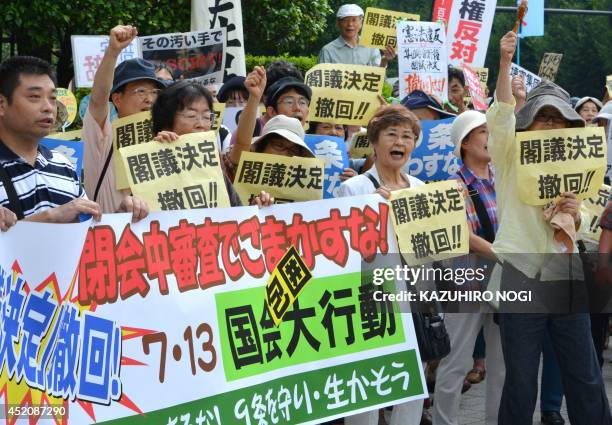 Protesters hold placards demanding the "withdraw of the cabinet decision" and shout anti-Abe government slogans during a rally in front of the...