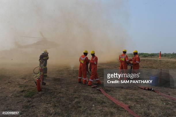 Indian fire officials of Oil and Natural Gas Corporation react as the helicopter transporting Indian Minister for Petroleum and Natural Gas, M...