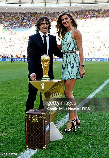 Former Spanish international Carles Puyol and model Gisele Bundchen present the World Cup from a Louis Vuitton travel case prior to the 2014 FIFA...