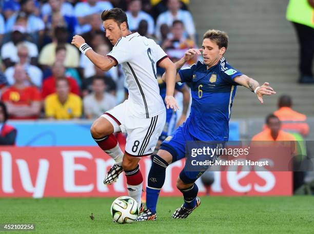 Mesut Oezil of Germany and Lucas Biglia of Argentina compete for the ball during the 2014 FIFA World Cup Brazil Final match between Germany and...