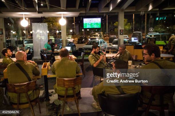 Israeli soldiers watch the 2014 World Cup final match between Germany and Argentina in a cafe on the sixth day of Israel's operation 'Protective...