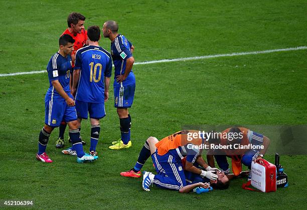 Gonzalo Higuain of Argentina receives treatment as teammates Lionel Messi, Sergio Aguero and Javier Mascherano appeal to referee Nicola Rizzoli...