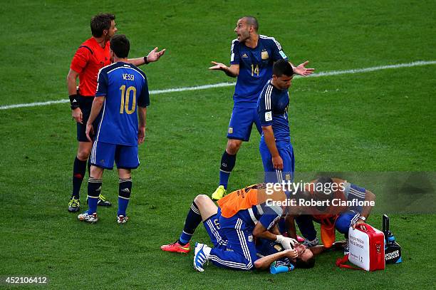 Gonzalo Higuain of Argentina receives treatment as teammates Lionel Messi, Sergio Aguero and Javier Mascherano appeal to referee Nicola Rizzoli...