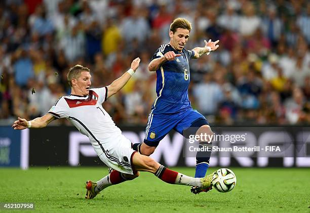 Lucas Biglia of Argentina is tackled by Bastian Schweinsteiger of Germany during the 2014 FIFA World Cup Brazil Final match between Germany and...