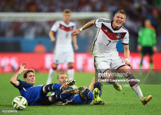 Lucas Biglia and Javier Mascherano of Argentina challenge Bastian Schweinsteiger of Germany during the 2014 FIFA World Cup Brazil Final match between...