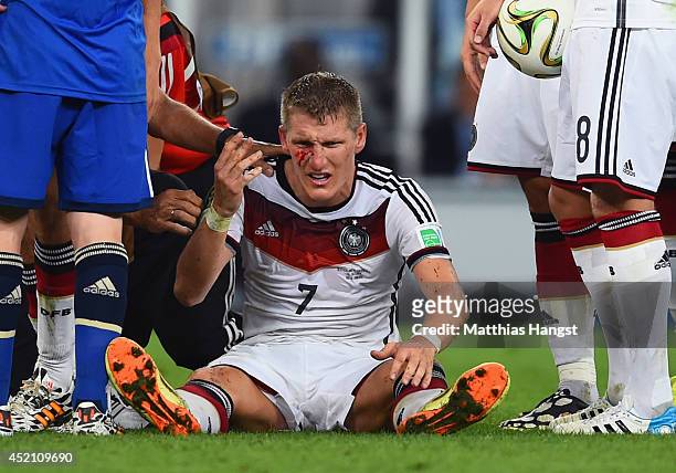 Bastian Schweinsteiger of Germany receives treatment after a collision during the 2014 FIFA World Cup Brazil Final match between Germany and...