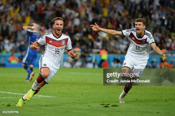 Mario Goetze of Germany celebrates scoring his team's first goal with Thomas Mueller during the 2014 FIFA World Cup Brazil Final match between...