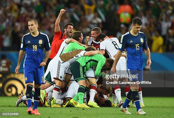 Germany celebrate after defeating Argentina in extra time 1-0 as Rodrigo Palacio and Martin Demichelis of Argentina look on during the 2014 FIFA...