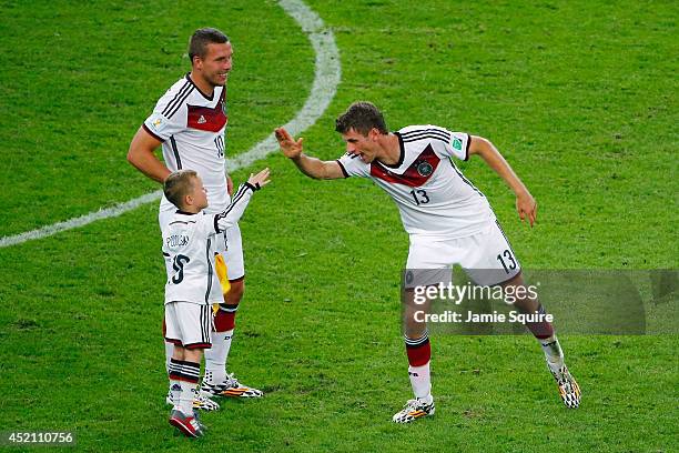 Thomas Mueller of Germany celebrates defeating Argentina 1-0 in extra time with Lukas Podolski and his son Louis Podolski during the 2014 FIFA World...