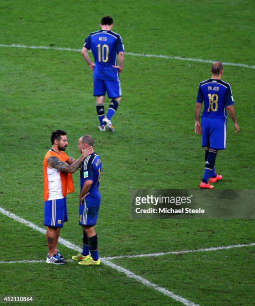 Ezequiel Lavezzi of Argentina consoles teammate Javier Mascherano as Lionel Messi and Rodrigo Palacio look on after being defeated by Germany 1-0 in...