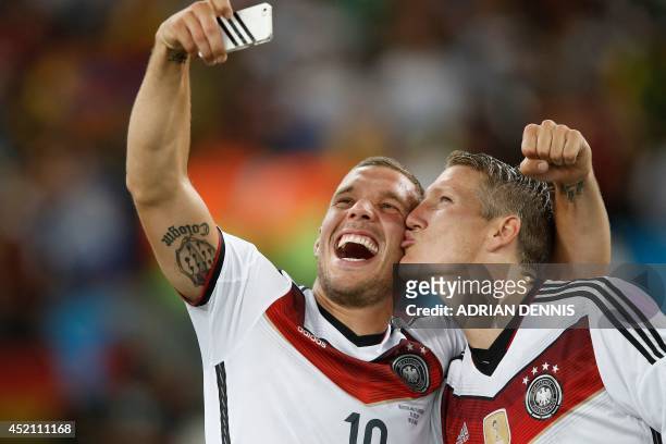 Germany's midfielder Bastian Schweinsteiger and teammate forward Lukas Podolski take a 'selfie' after their victory in extra-time in the final...