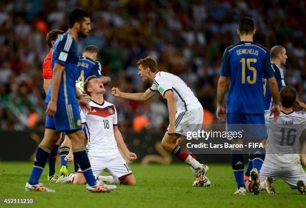 Toni Kroos and players of Germany celebrate while Argentina players show dejection after the 2014 FIFA World Cup Brazil Final match between Germany...