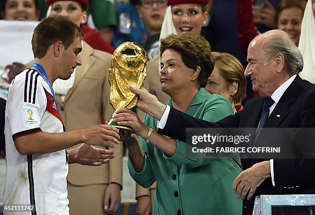 Germany's defender and captain Philipp Lahm is presented with the World Cup trophy by Joseph Blatter FIFA President and Brazil's President Dilma...