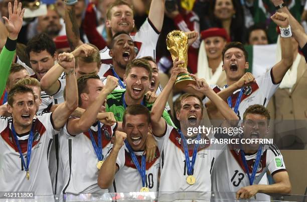 Germany's defender and captain Philipp Lahm holds up the World Cup trophy as he celebrates on with his teammates after winning the 2014 FIFA World...