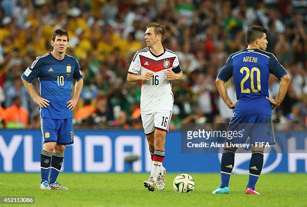 Philipp Lahm of Germany celebrates his team's first goal while Lionel Messi and Sergio Aguero of Argentina show their dejections during the 2014 FIFA...