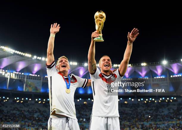 Bastian Schweinsteiger and Lukas Podolski of Germany celebrate with the World Cup trophy after the 2014 FIFA World Cup Brazil Final match between...
