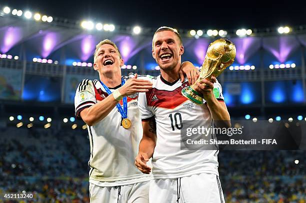 Bastian Schweinsteiger and Lukas Podolski of Germany celebrate with the World Cup trophy after the 2014 FIFA World Cup Brazil Final match between...