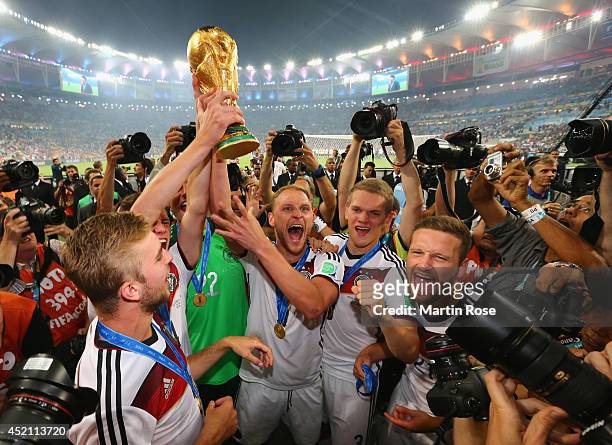 Benedikt Hoewedes of Germany raises the World Cup trophy with teammates after defeating Argentina 1-0 in extra time during the 2014 FIFA World Cup...