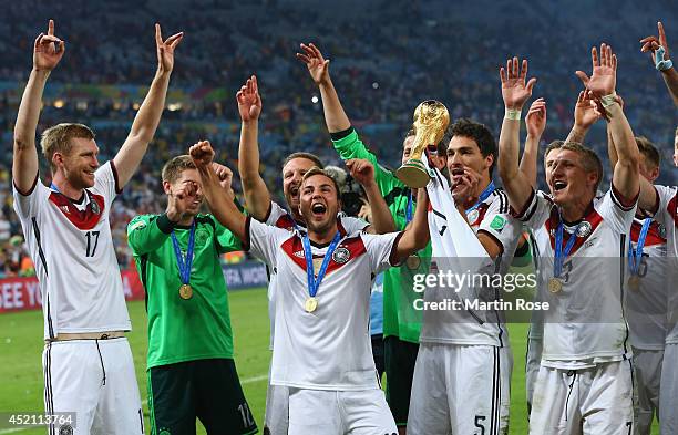 Mario Goetze of Germany raises the World Cup trophy with teammates Per Mertesacker, Ron-Robert Zieler, Shkodran Mustafi, Roman Weidenfeller, Mats...