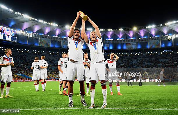 Mats Hummels and Andre Schuerrle of Germany lift the World Cup trophy to celebrate after the 2014 FIFA World Cup Brazil Final match between Germany...