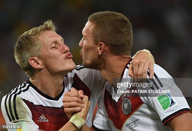 Germany's midfielder Bastian Schweinsteiger and Germany's forward Lukas Podolski celebrate after winning the 2014 FIFA World Cup final football match...