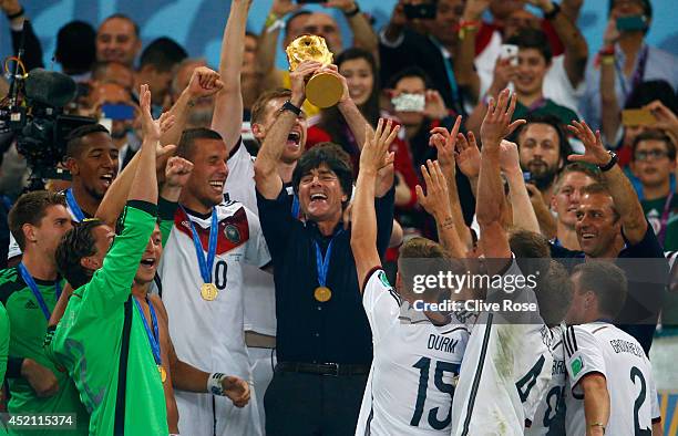 Head coach Joachim Loew of Germany raises the World Cup trophy after defeating Argentina 1-0 in extra time during the 2014 FIFA World Cup Brazil...
