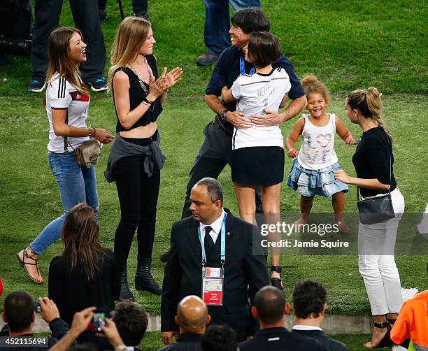 Head coach Joachim Loew of Germany hugs Kathrin Gilch, girlfriend of Manuel Neuer of Germany, as Montana Yorke, girlfriend of Andre Schuerrle of...