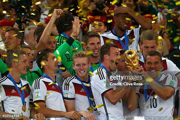Lukas Podolski of Germany raises the World Cup trophy and celebrates with teammates after defeating Argentina 1-0 in extra time during the 2014 FIFA...