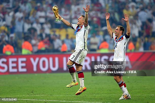 Bastian Schweinsteiger of Germany holds up the World Cup trophy alongside team-mate Philipp Lahm of Germany after the 2014 FIFA World Cup Brazil...