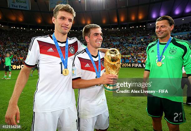 Thomas Muller , Philipp Lahm and Roman Weidenfeller of Germany celebrate with the World Cup trophy after the 2014 FIFA World Cup Brazil Final match...