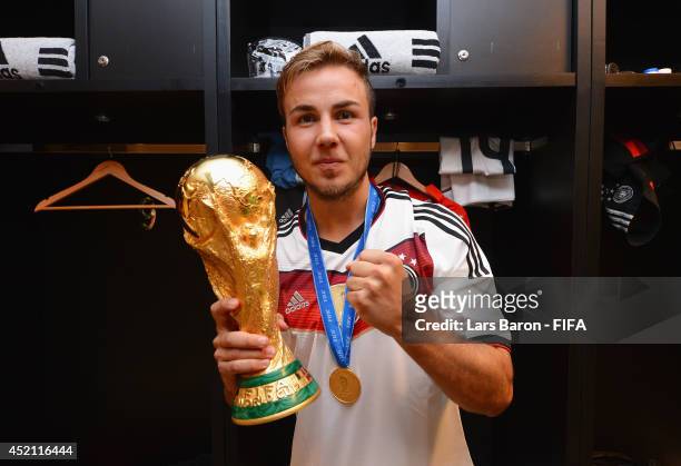Mario Goetze of Germany holds up the World Cup trophy in the Germany dressing room after the 2014 FIFA World Cup Brazil Final match between Germany...