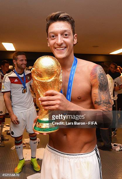 Mesut Oezil of Germany holds up the World Cup trophy in the Germany dressing room after the 2014 FIFA World Cup Brazil Final match between Germany...