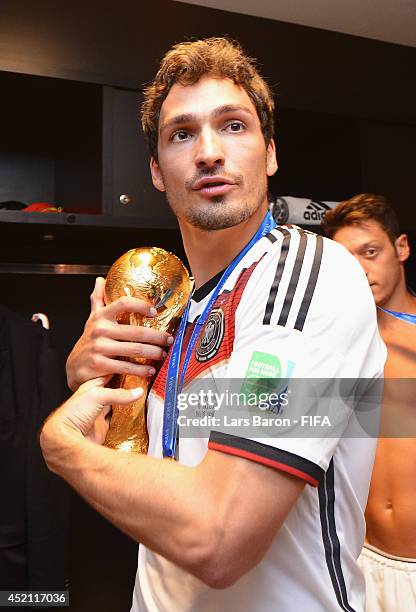 Mats Hummels of Germany holds up the World Cup trophy in the Germany dressing room after the 2014 FIFA World Cup Brazil Final match between Germany...